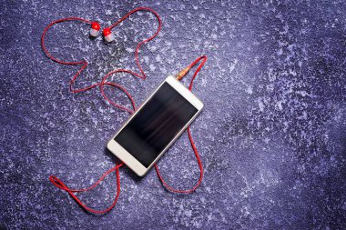 Hareket eden telefon ile müzik dinlemek için kulaklık. Kırmızı kablo kelebek veya kalp şeklinde. Alan, yazıt için kopyalayın. Onarılan jack.
