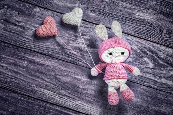 Amigurumi di coniglio lavorato a maglia con due palloncini su fondo di legno . — Foto Stock