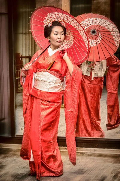 Geisha i röd kimono med parasol — Stockfoto