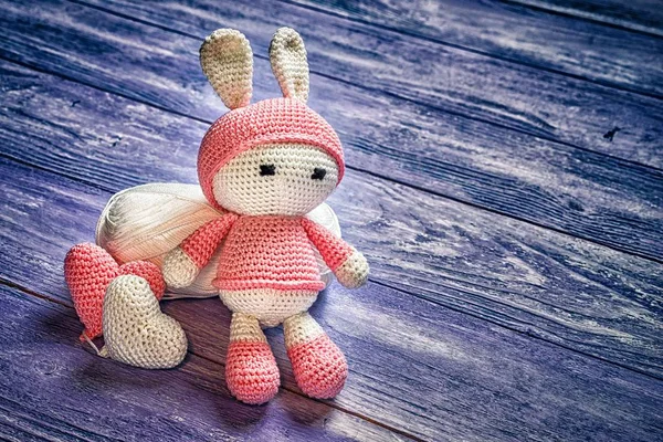 Bambola giocattolo fatto a mano uncinetto coniglio seduto su una matassa di lana, due cuori all'uncinetto, spazio per il testo — Foto Stock