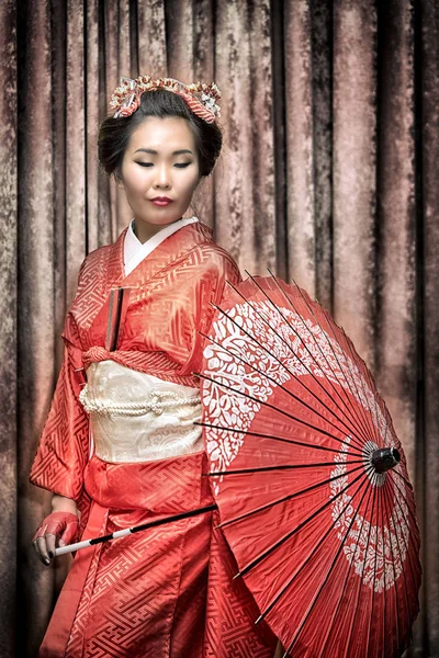 Aziatische vrouw in traditionele rode kimono met parasol — Stockfoto