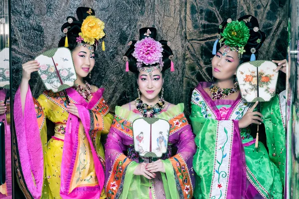 Três atraente asiático mulheres vestindo japonês quimono segurando tradicional fãs — Fotografia de Stock