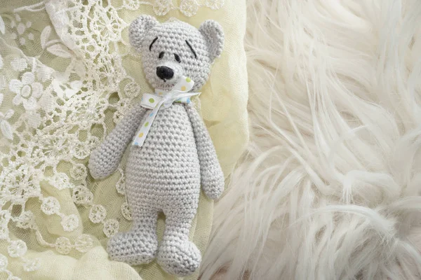 Amigurumi bear toy laying on a soft lace and fur with copy space — Stock Photo, Image
