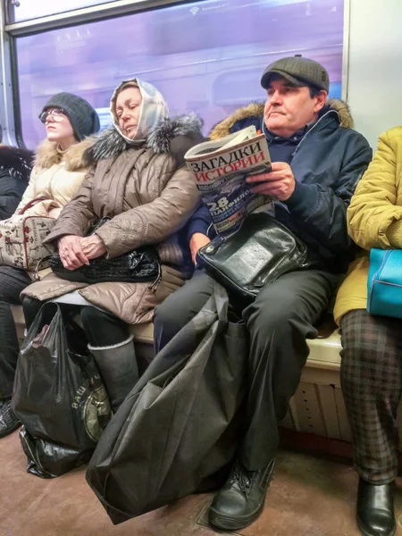 Moscou, Rússia - 28 de novembro de 2016: reportagem do metrô de Moscou. Passageiros a viajar no comboio. Homem lendo um jornal sentado em uma fila de passageiros . — Fotografia de Stock