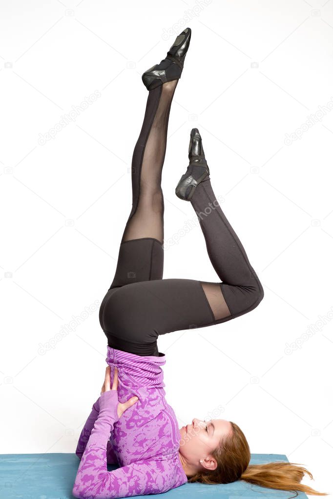 Fitness, stretching workout, attractive woman in violet and black sportswear working out in sports club, doing shoulderstand exercise, Viparita Karani, Upside-Down Seal pose