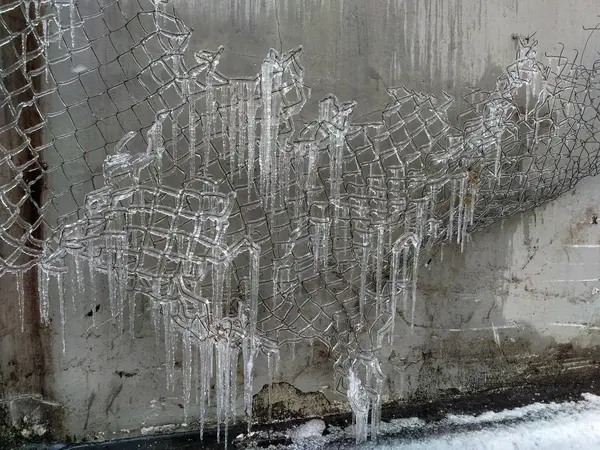Hintergrund in Form von Eiszapfen auf dem Gitter und neutraler grauer Wand — Stockfoto