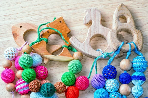 Ожерелье из вязаных бусин и деревянных игрушек для ребенка, сидящего в стропе. Связанные бусины. Рогатые ожерелья . — стоковое фото