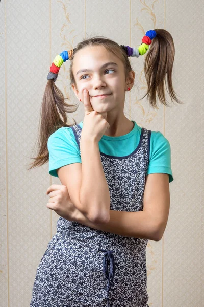 Menina de 11 anos com tranças como Pippi Longstocking é pensativo, pressionando um dedo em sua bochecha. o conceito de tomada de decisão . — Fotografia de Stock