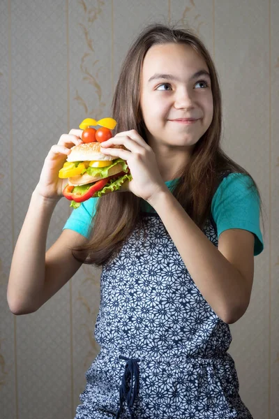 Menina de 11 anos com um hambúrguer na mão olhando para cima — Fotografia de Stock