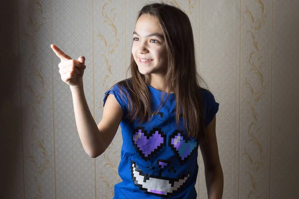 Sorrindo menina de 11 anos apontando o dedo para o lado — Fotografia de Stock