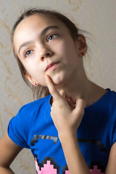 Nahaufnahme Porträt eines 11-jährigen Mädchens, das nachdenklich nach oben blickt und einen Finger an ihre Wange lehnt. — Stockfoto