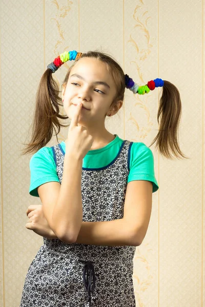 Retrato de uma menina de 11 anos com caudas engraçadas em seu cabelo, coloque o dedo nos lábios e pense com uma expressão travessa — Fotografia de Stock