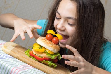 11 yaşında bir kız, bir hamburger yiyen bir gülen yüz domates gözlü olarak portresi
