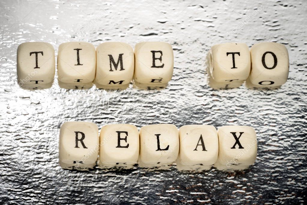 Time to relax text on a wooden cubes on a shiny silver background