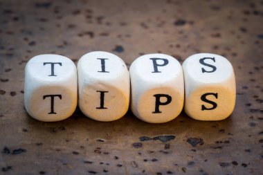 Tips text on wooden cubes on a brown cork background