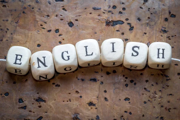 Kahverengi bir mantar arka plan üzerinde bir iplik üzerinde sinirli ahşap küpler üzerinde İngilizce kelime