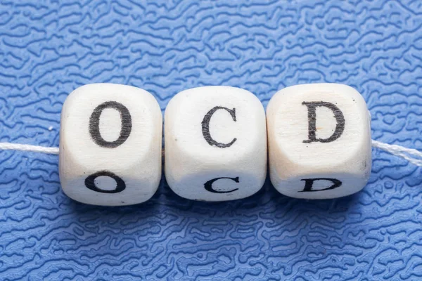Palavra ocd (transtorno obsessivo compulsivo) em um cubos de madeira em um fundo azul — Fotografia de Stock