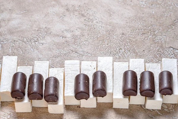 Piano keys laid out chocolates candy and marshmallows paste, on a neutral beige cement background with plenty of copy space above. Sweet music concept. — Stock Image Piano keys laid out chocolates candy and marshmallows paste, on a neutral beige cement background with plenty of copy space above. Sweet music concept. Royalty Free Stock Photos