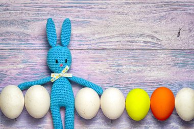 Amigurumi oyuncak Paskalya tavşanı üst üste ahşap bir masa - kopya alanı ile Paskalya arka plan üzerinde beyaz ve renkli yumurta ile