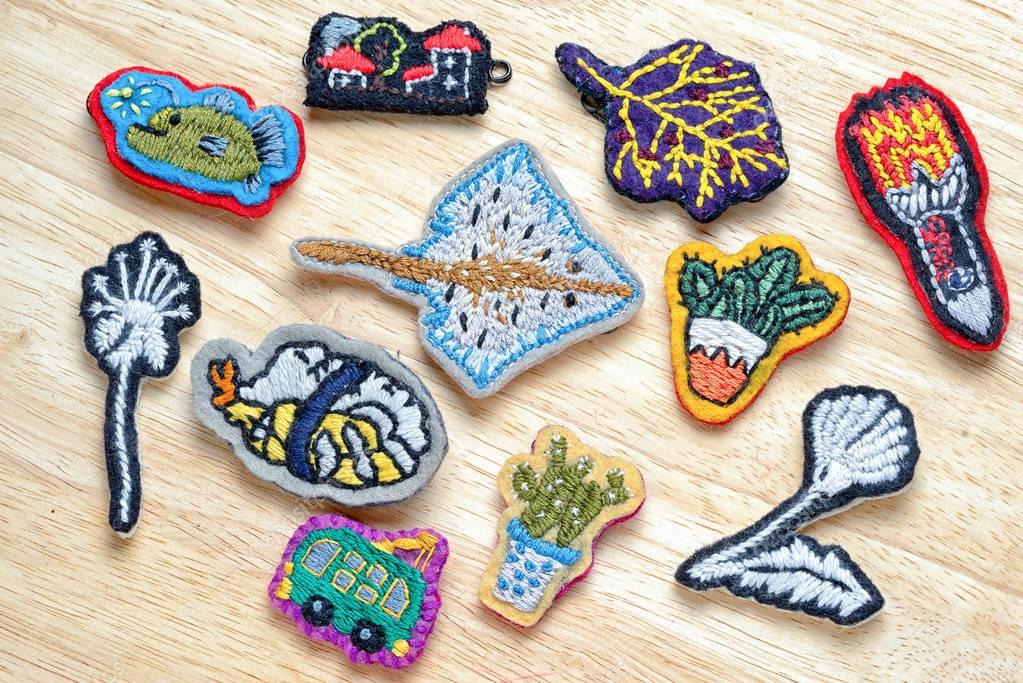 Group of homemade embroidery brooches on a wooden table