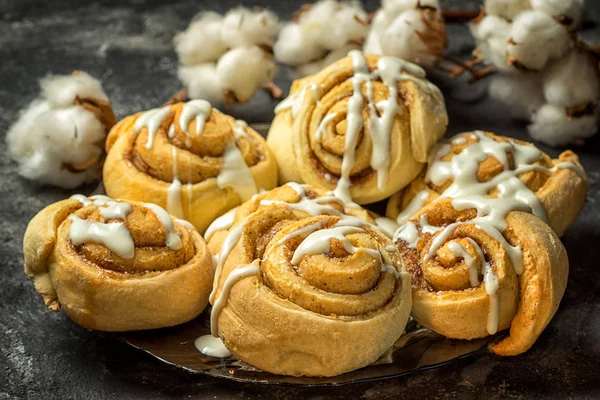 Cinnamon rolls in a plate, on a dark background with cement cotton boxes behind. — Stock Photo, Image