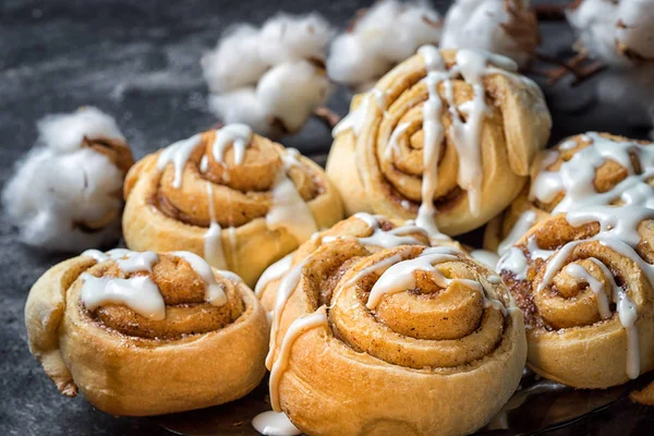 Close up cinnamon rolls in a plate, on a dark background with cement cotton boxes behind. — Stock Photo, Image