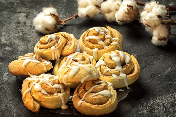 Cinnamon rolls on the plate, on a dark cement table, cotton boxes behind. — Stock Photo, Image