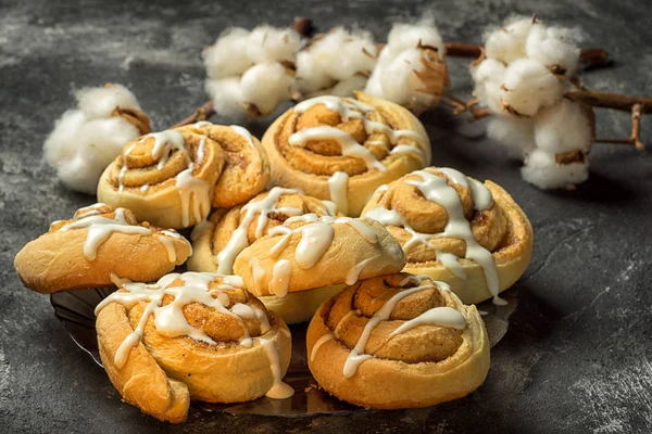 Fresh delicious cinnamon rolls on the plate on a dark black cement background with cotton boxes behind — Stock Photo, Image