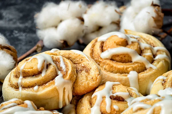 Close up cinnamon rolls on the plate, on a dark cement table, cotton boxes behind. — Stock Photo, Image