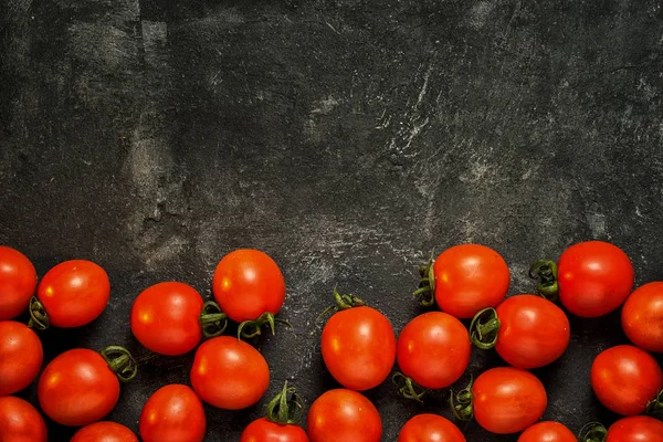 stock image food black dark cement background with tomatoes along the bottom edge and copy space for your text