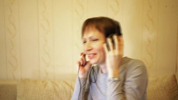 Счастливая женщина средних лет слушает музыку в наушниках и переходит к ритму — стоковое видео