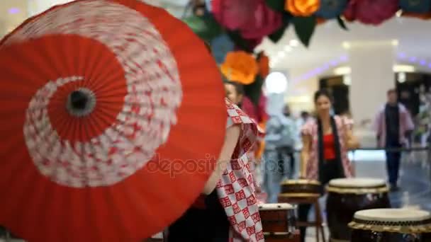 Moscou, Rússia - 4 de março de 2017: grupo de garotas japonesas bateristas Taiko se apresentam no shopping center "Oceania" na abertura de uma nova loja UNIQLO Unique Clothing Warehouse. Dança com guarda-chuva . — Vídeo de Stock