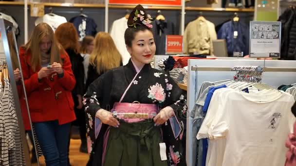 Moscou, Russie - 5 mars 2017 : Deux geisha faisant leurs courses dans le magasin de vêtements UNIQLO parmi les vêtements et les consommateurs ordinaires. La performance est programmée pour l'ouverture d'un nouveau 15ème magasin en Russie . — Video