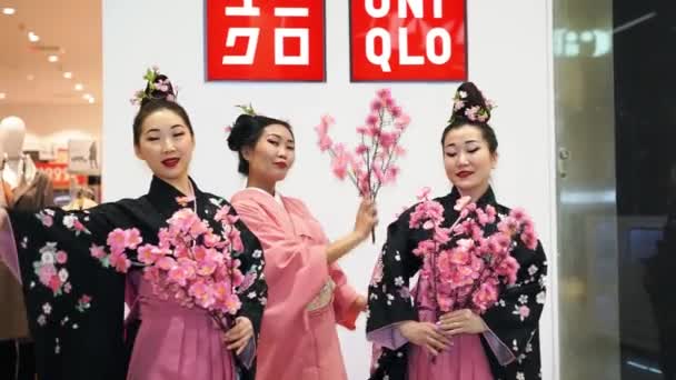 Moscú, Rusia - 5 de marzo de 2017: Tres geishas en kimono tradicional japonés con ramas de sakura en la entrada de la tienda uniqlo. El rendimiento está programado para la apertura de una nueva tienda 15 en Rusia . — Vídeo de stock