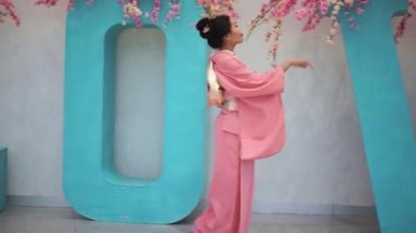 Duvar ve büyük harflerle kiraz çiçekleri ile yakın yürüyüş şemsiye ile pembe kimono içinde geyşa.