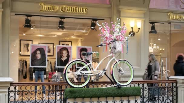 Moscow, Russia - March 15, 2017: Juicy Couture store in GUM (department store) or Central Universal Department Store. People walk near the storefront. Decoration in the form of a bicycle with flowers. — Stock Video