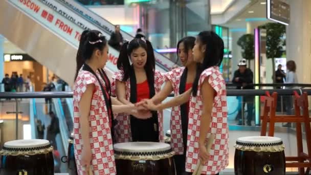 Moscú, Rusia - 25 de marzo de 2017: Japonesas bateristas taiko niñas en el centro comercial Caleidoscopio en la apertura de una nueva tienda UNIQLO. Las niñas gritan Taiko inspiración y recoger muslos . — Vídeos de Stock