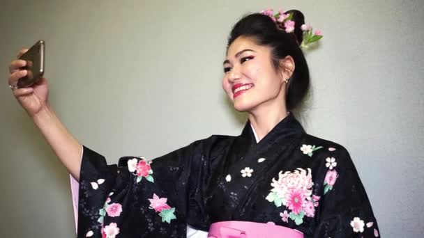 Beautiful geisha in traditional japanese kimono making selfie — Stock Video