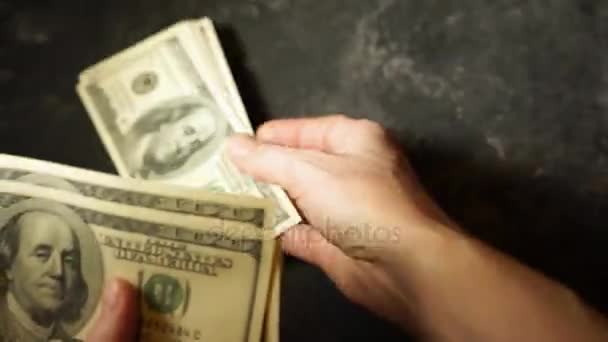 Ženské ruce spočítat Spojené státy sto dolarové bankovky. Každý tisíc dolarů jsou nacpané v samostatných hromadách na stole. Zrychlený pohyb.