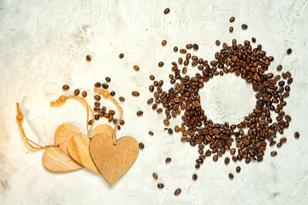 Três corações de madeira como um símbolo de amor de café e um círculo de grãos de café, visão superior. Espaço de cópia . — Fotografia de Stock