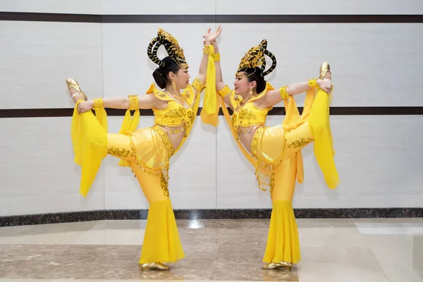 Wo красивая девушка актриса в желтых традиционных китайских костюмах сцены стоя в акробатической позе с одной ногой вверх — стоковое фото