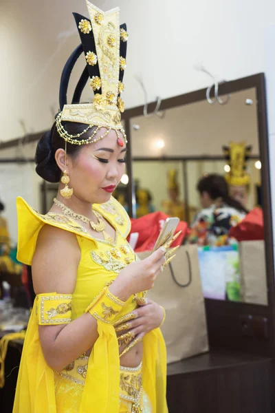 Atriz no camarim. Jovem mulher asiática em amarelo tradicional chinês traje de palco usando seu smartphone . — Fotografia de Stock