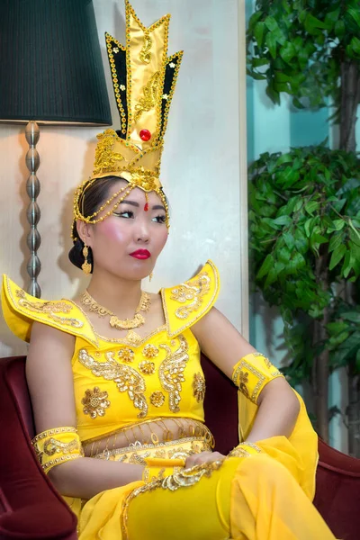 Mujer asiática joven en traje de escenario chino tradicional amarillo sentado en el sillón — Foto de Stock