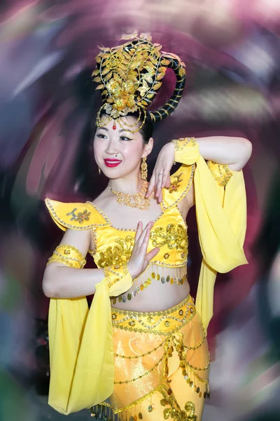 Aziatische danser actrice in een gele traditionele chinese fase kostuum tegen wazig plek achtergrond — Stockfoto