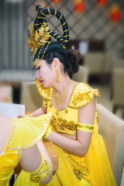Attrice asiatica in costume tradizionale cinese giallo menu di lettura al ristorante, vista profilo — Foto Stock