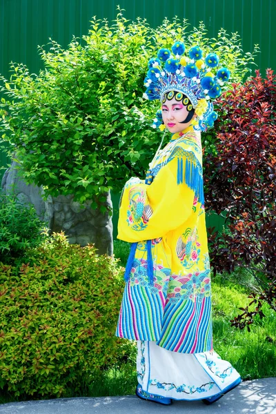 Hermosa chica china en vestido chino tradicional y sombrero de pie al aire libre —  Fotos de Stock