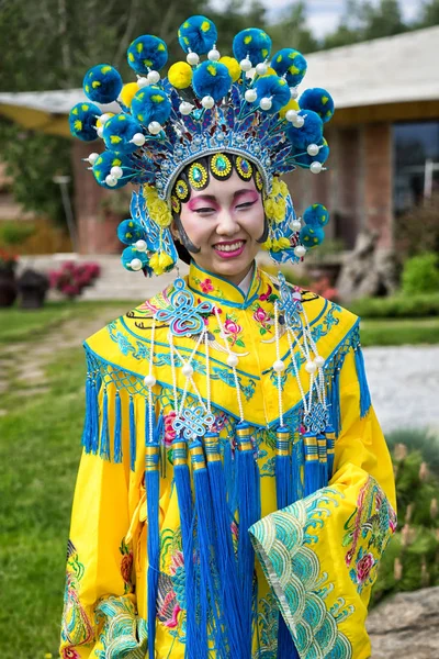 美丽的中国女孩，在传统的中国服饰与长长的袖子和帽子常设户外 — 图库照片