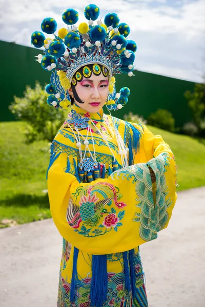 Vacker kinesisk flicka i traditionell kinesisk klänning med långa ärmar och hatt stående utomhus — Stockfoto