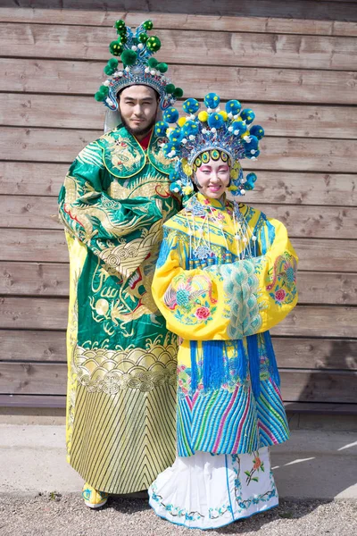 Kinesisk man och kvinna i traditionella dräkter står nära trävägg — Stockfoto