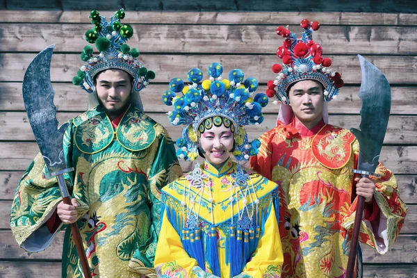 Grupp av tre asiatiska människor män och kvinna står i rad och hälsning utomhus i traditionella kinesiska dräkter — Stockfoto
